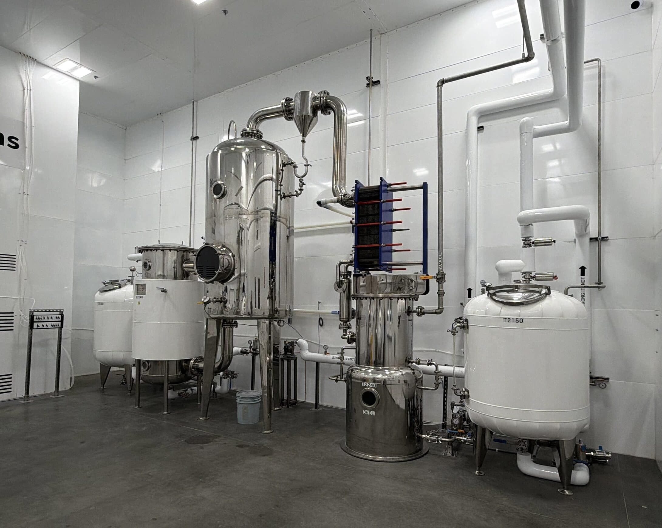 Stainless evaporator, plate heat exchanger and jacketed tanks against the white panel walls of the Loveland cleanroom