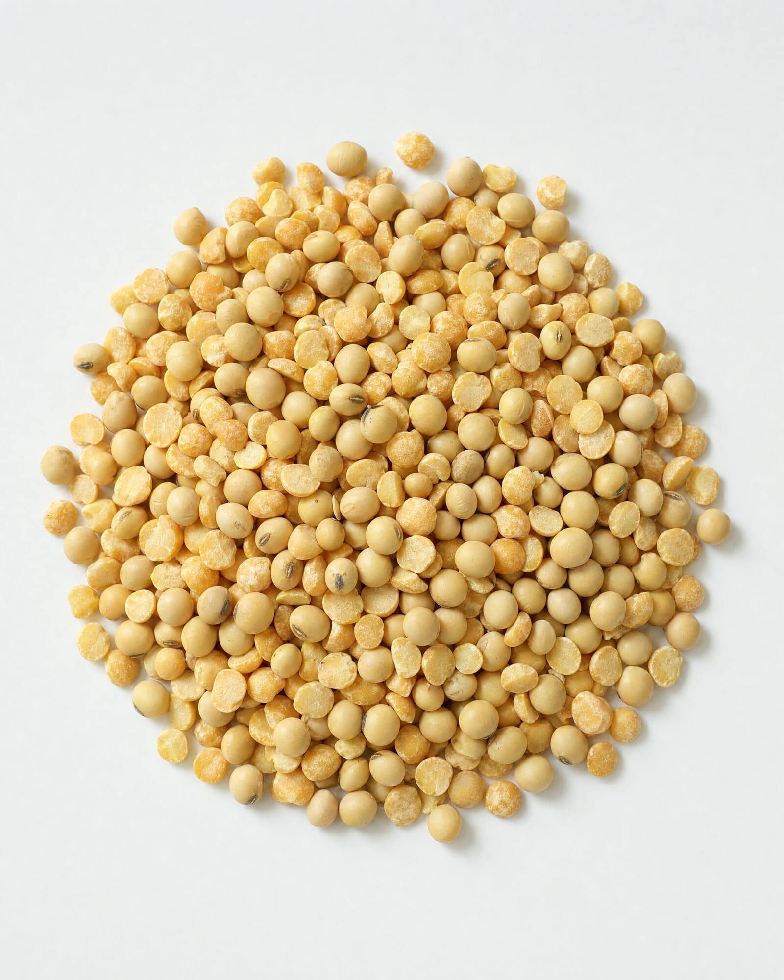 Yellow split peas and soybeans in a mound on a white surface
