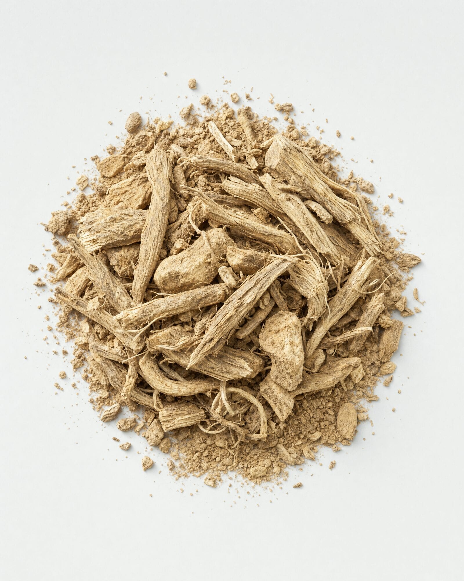 Dried kava root pieces and root powder on a white surface
